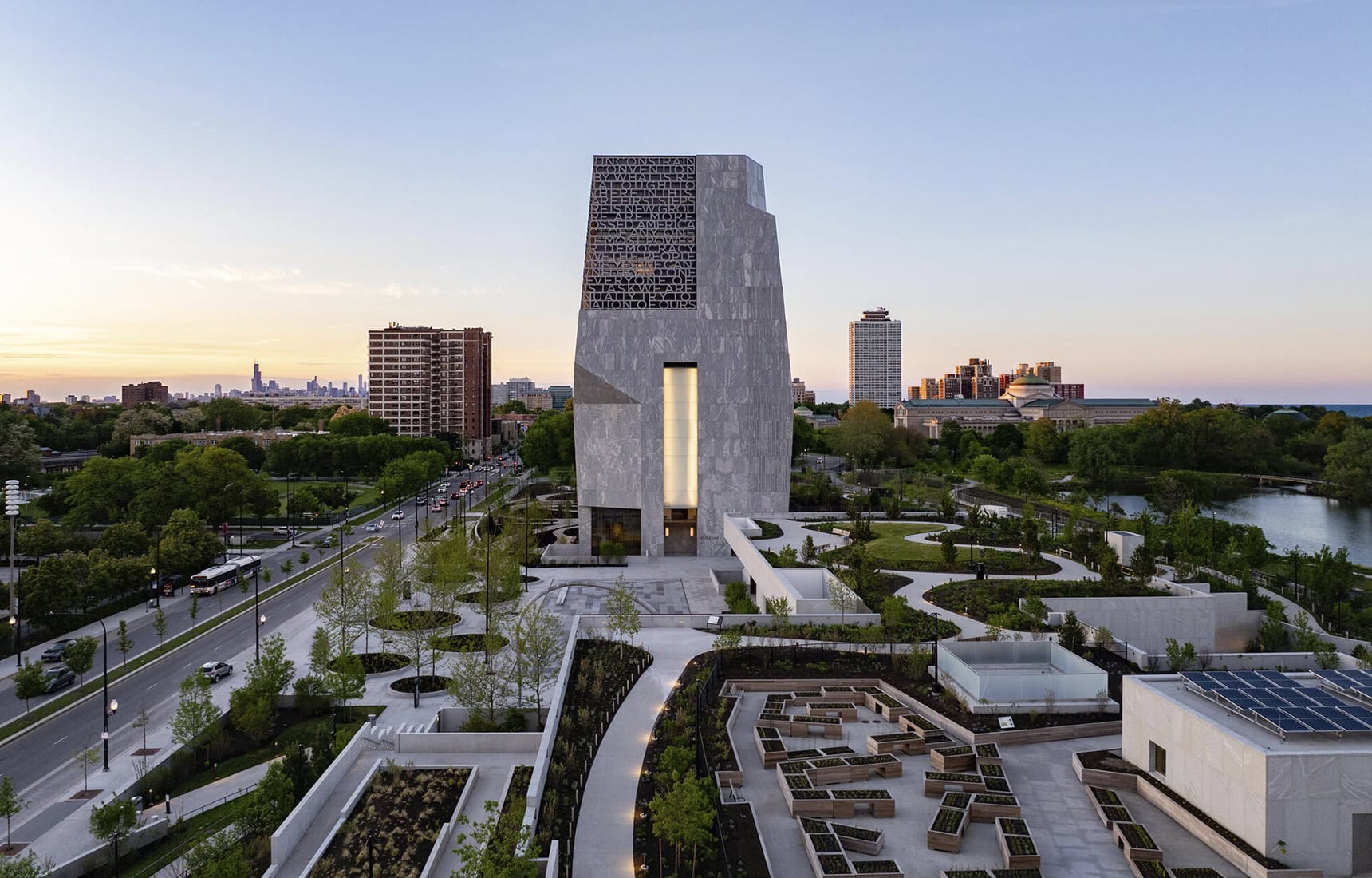 Aerial view at sunset of the Obama Presidential Center, its Museum Tower and plaza aligned along a central axis with Chicago beyond