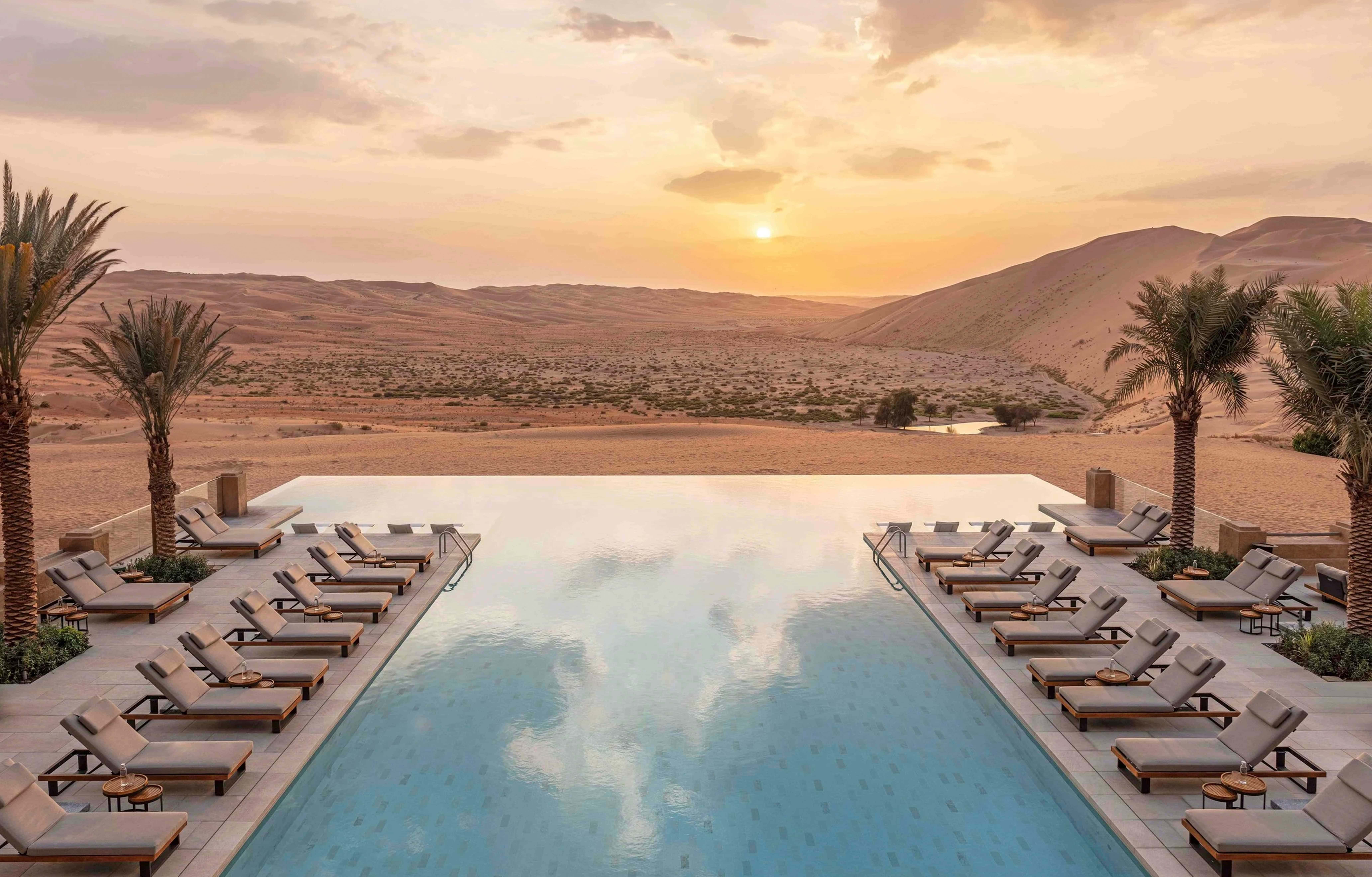 The infinity pool overlooking the dunes at sunset at Qasr Al Sarab Desert Resort by Anantara