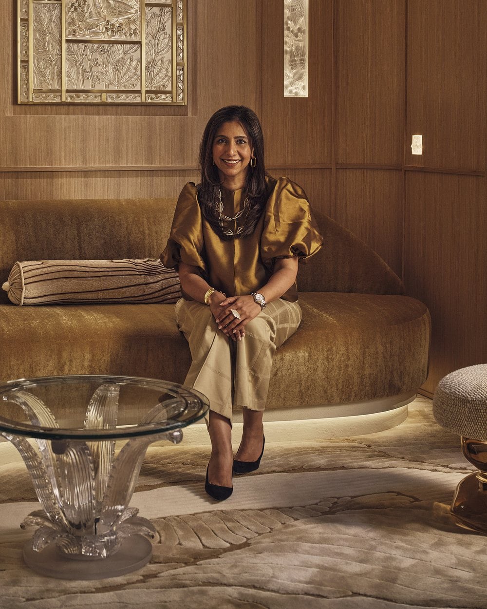 Charu Gandhi, founder of Elicyon, seated on a velvet sofa in a timber-panelled interior